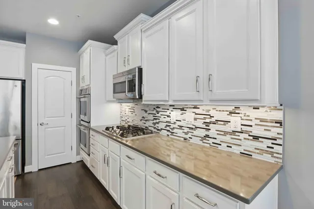 a kitchen with granite countertop white cabinets and stainless steel appliances