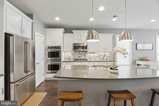 a kitchen with kitchen island granite countertop a sink cabinets and stainless steel appliances