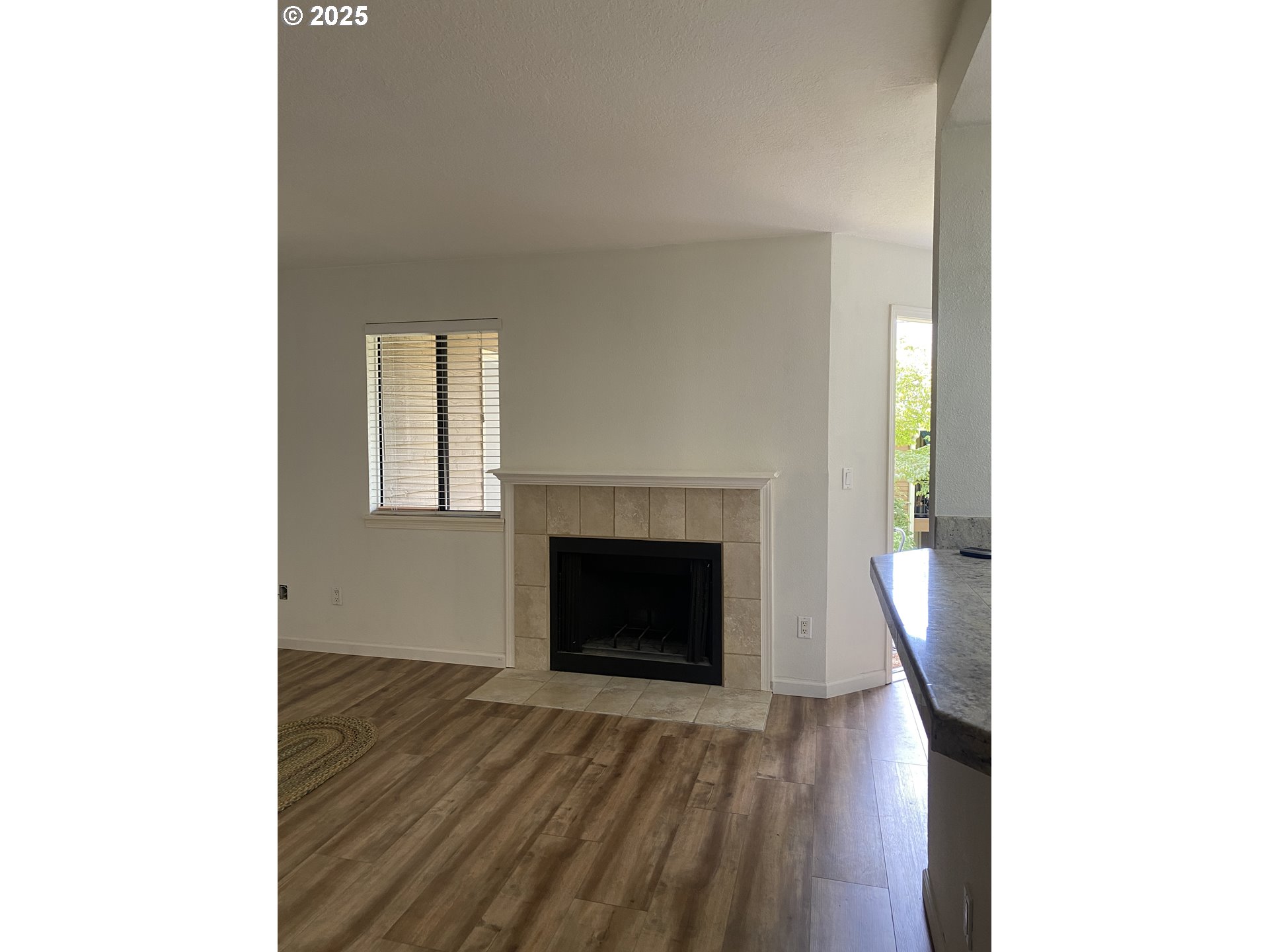 9872 Southeast Talbert Street Clackamas, OR 97015 - Photo 6 of 38 a view of an empty room with wooden floor and a fireplace