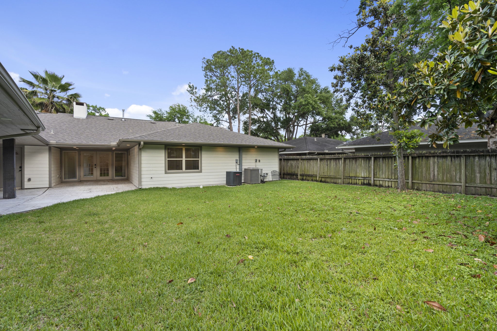 2402 Chimney Rock Road Houston, TX 77057 - Photo 33 of 36 Spacious backyard with a large open lawn, mature trees, and a fully fenced perimeter—perfect for outdoor entertaining, play, or relaxing in a private setting.