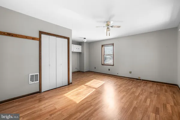 an empty room with wooden floor chandelier fan and windows