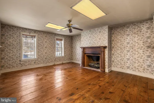 a view of an empty room with window and wooden floor