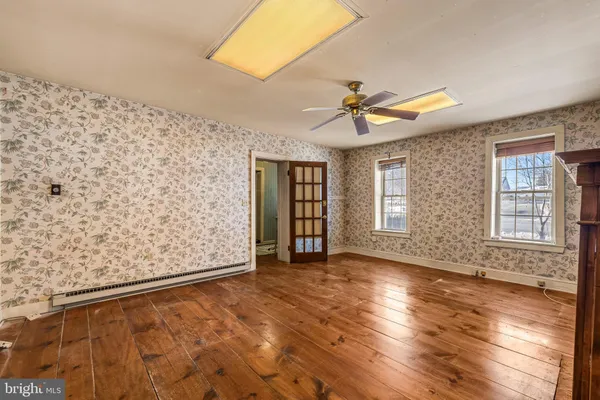 a view of an empty room with window and wooden floor