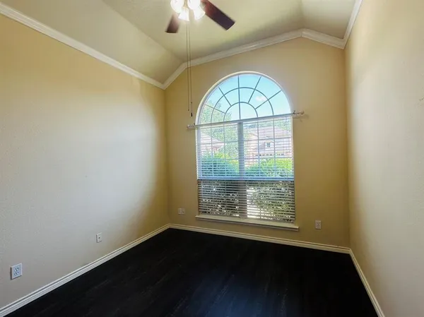 an empty room with wooden floor fan and windows