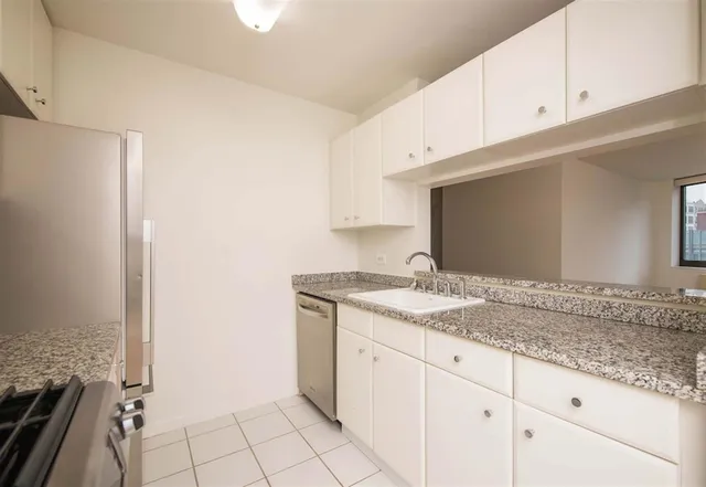 a bathroom with a granite countertop sink and white cabinets