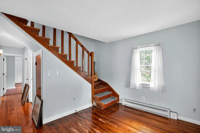 a view of an empty room with wooden floor and stairs
