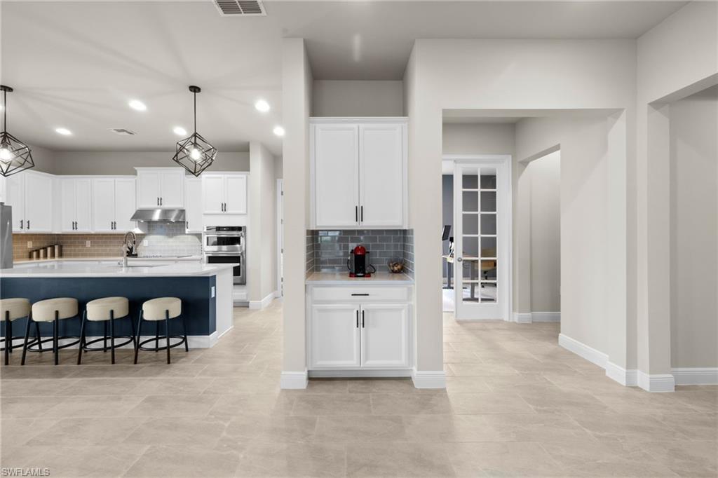 3419 Pilot Circle Naples, FL 34120 - Photo 24 of 39 a large white kitchen with stainless steel appliances kitchen island granite countertop a refrigerator and a stove top oven