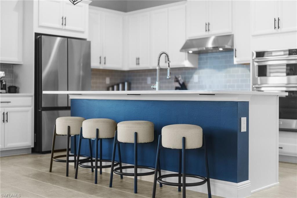 3419 Pilot Circle Naples, FL 34120 - Photo 4 of 39 a kitchen with stainless steel appliances granite countertop a dining table chairs refrigerator and sink