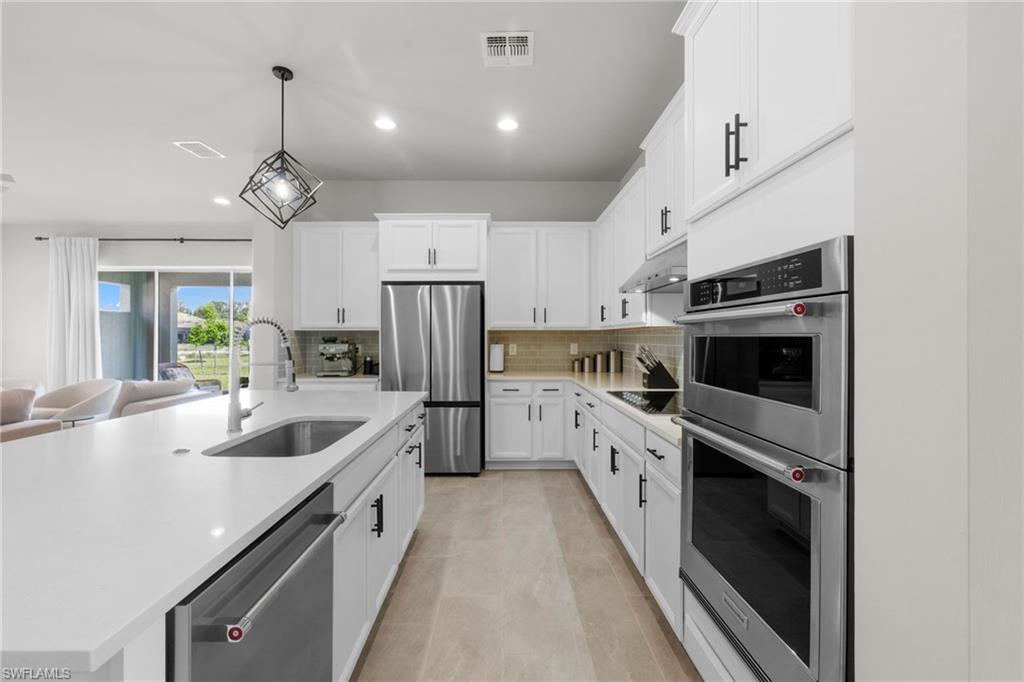 3419 Pilot Circle Naples, FL 34120 - Photo 5 of 39 a kitchen with white cabinets and stainless steel appliances