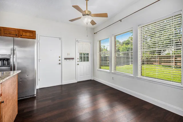 a view of an empty room with a window and wooden floor