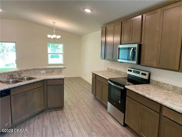 a kitchen with stainless steel appliances granite countertop a sink a stove a microwave and wooden floors
