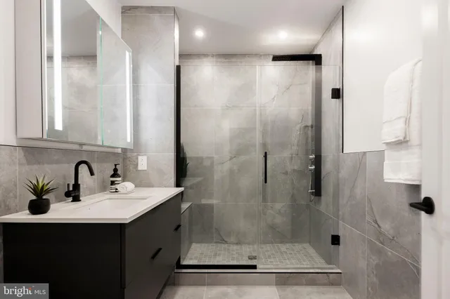 a bathroom with a shower sink vanity and mirror