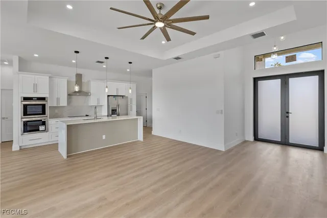 a view of kitchen with kitchen island wooden floors appliances and cabinets