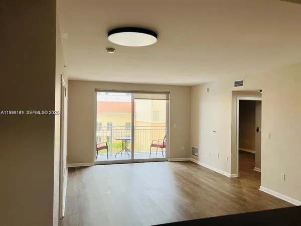 a view of an empty room with a window and wooden floor