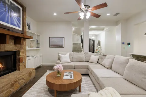 a living room with furniture a fireplace and a ceiling fan