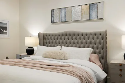 a bedroom with a large bed and a lamp on the dresser