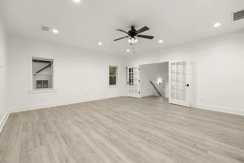 a view of empty room with wooden floor and fan