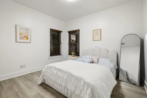 a bedroom with a bed and a large mirror next to a window