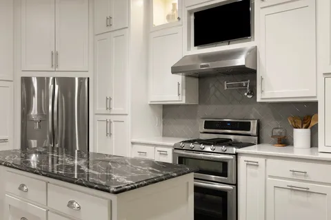 a kitchen with granite countertop a stove and a microwave