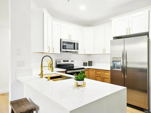 a kitchen with stainless steel appliances a stove a sink a refrigerator a window