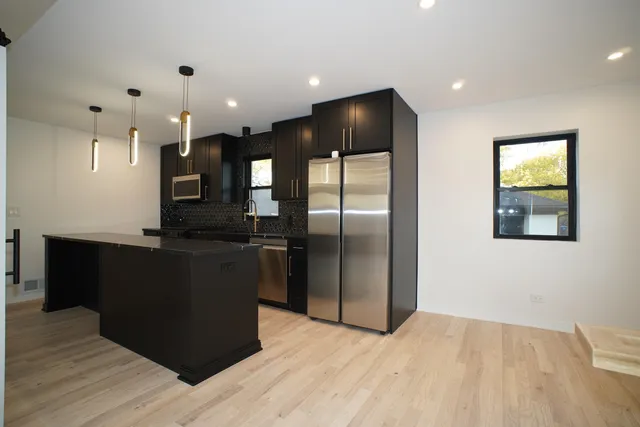 a kitchen with stainless steel appliances granite countertop a refrigerator and a wooden floor