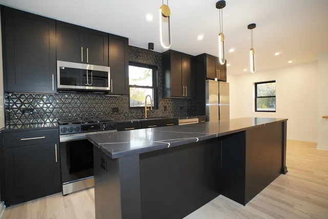 a kitchen with stainless steel appliances granite countertop a sink a stove and a refrigerator