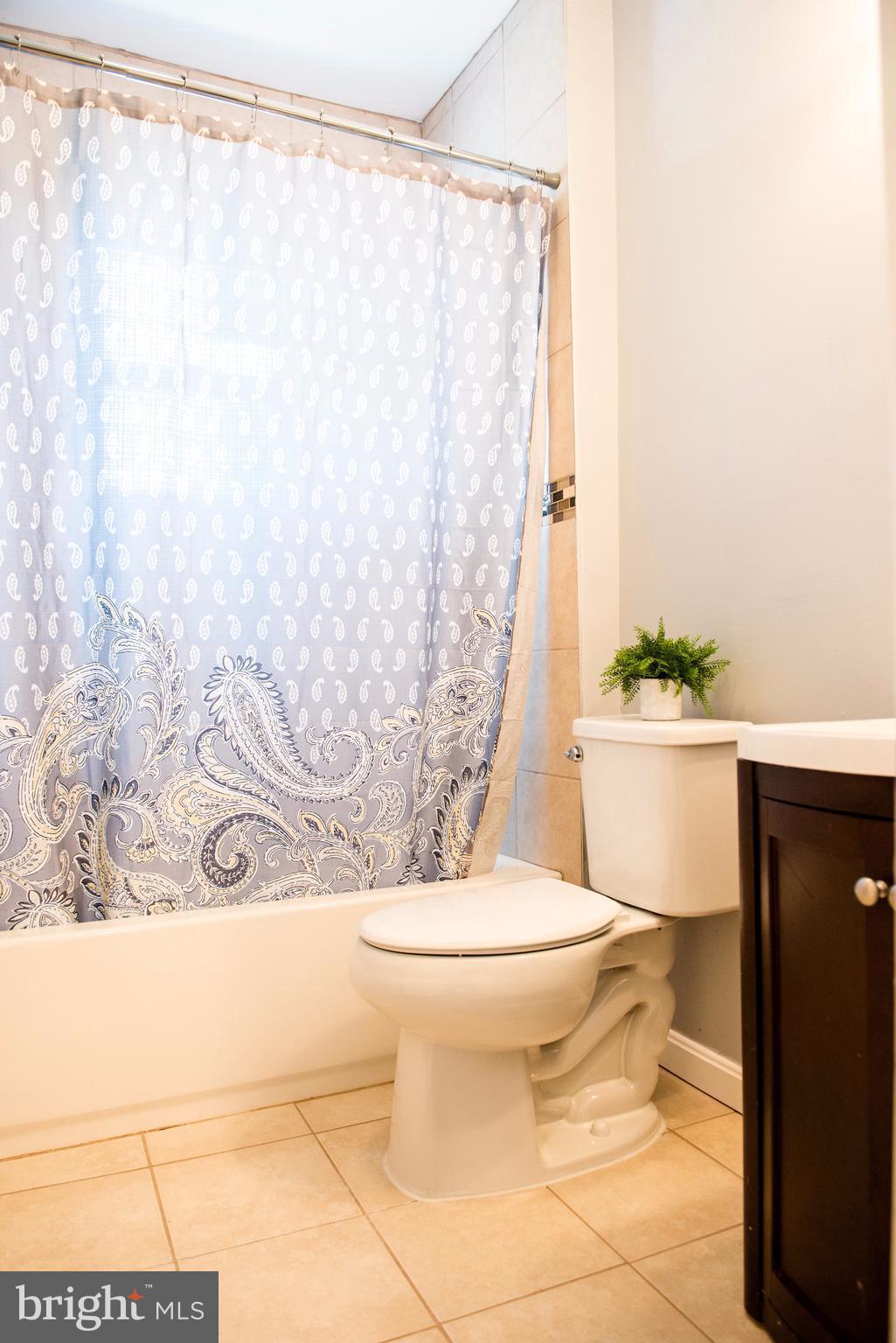 764 Edgewood Street Baltimore, MD 21229 - Photo 12 of 25 a white toilet sitting next to a shower curtain