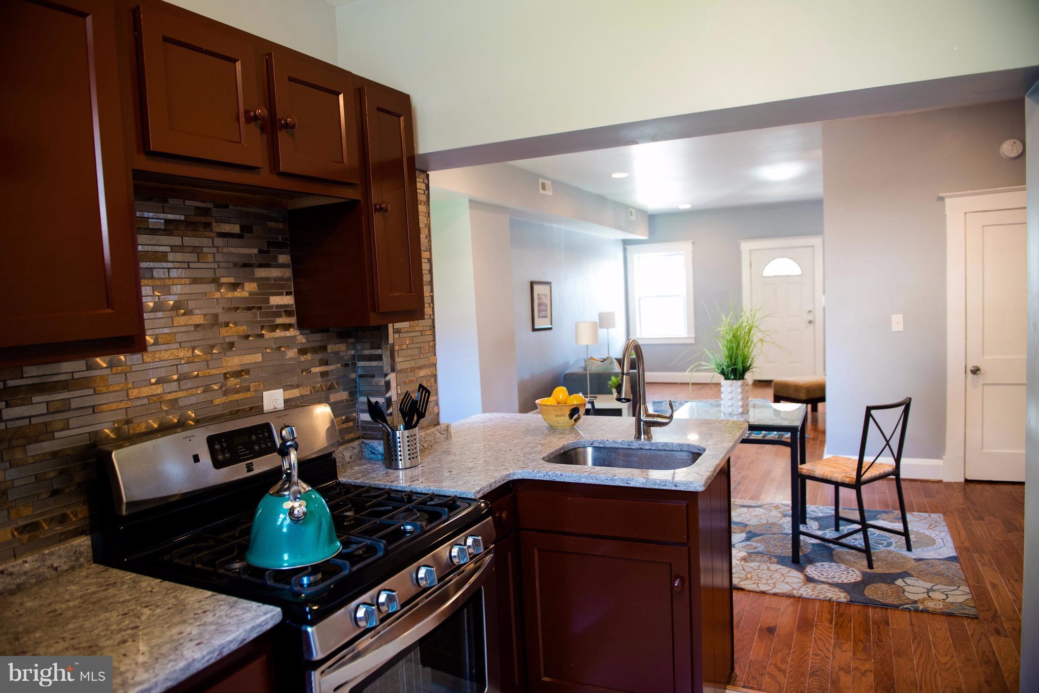 764 Edgewood Street Baltimore, MD 21229 - Photo 4 of 25 a kitchen with a dining table and chairs a stove with wooden floor