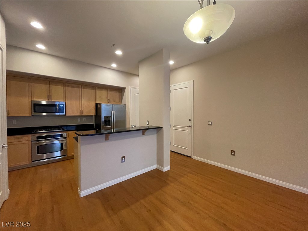 68 East Serene Avenue, Unit 225 Las Vegas, NV 89123 - Photo 5 of 22 Kitchen with a kitchen breakfast bar, stainless steel appliances, hanging light fixtures, light wood-style flooring, and a peninsula