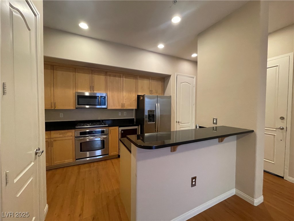 68 East Serene Avenue, Unit 225 Las Vegas, NV 89123 - Photo 7 of 22 Kitchen with light wood-style flooring, a breakfast bar, stainless steel appliances, recessed lighting, and a peninsula