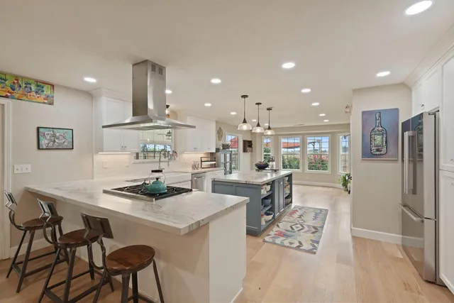 a kitchen with stainless steel appliances kitchen island granite countertop a sink a stove a refrigerator a microwave oven and a dining table