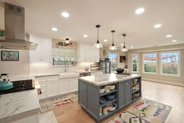 a large kitchen with kitchen island a stove a sink a center island and furniture
