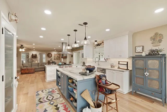 a room with stainless steel appliances kitchen island granite countertop a sink and cabinets