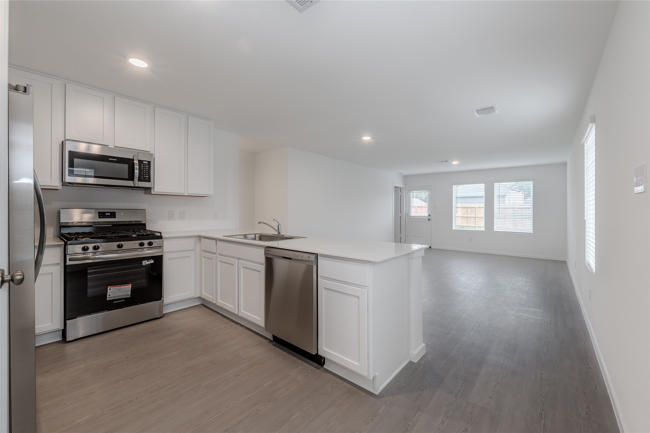 21358 Offida Lane New Caney, TX 77357 - Photo 6 of 26 a kitchen with stainless steel appliances kitchen island granite countertop a stove a sink and a refrigerator