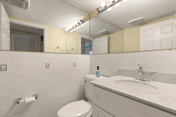 a bathroom with a granite countertop toilet sink and mirror