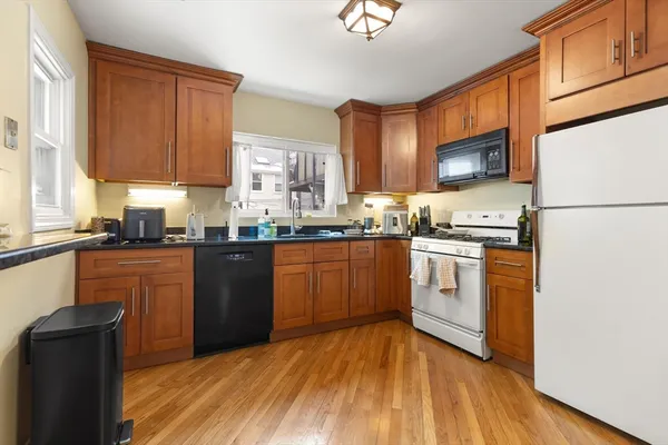 a kitchen with granite countertop wooden floors stainless steel appliances and sink