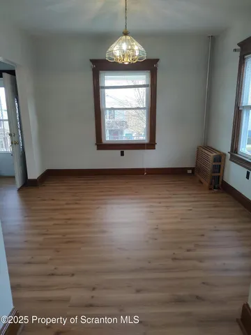 an empty room with wooden floor windows and entrance