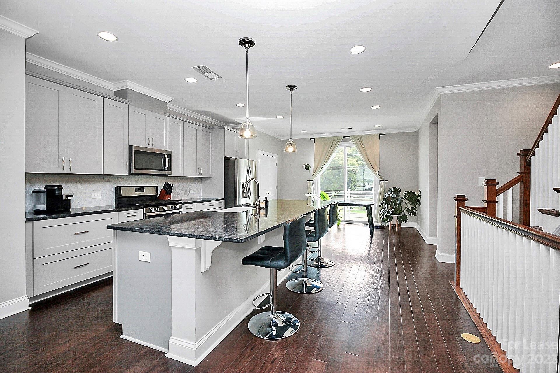 a kitchen with stainless steel appliances granite countertop a stove top oven a refrigerator a sink and cabinets