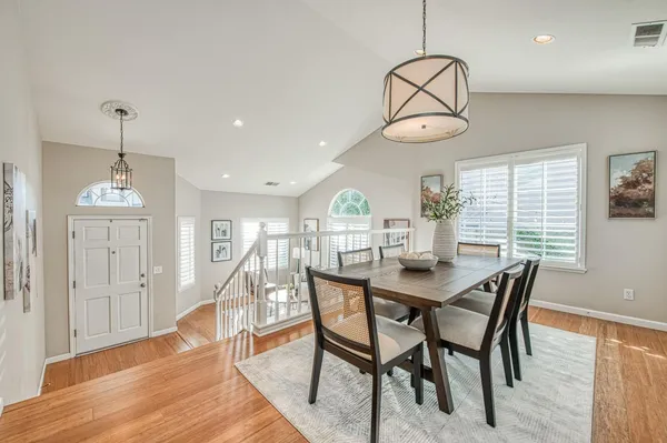 a dining room with wooden floor a chandelier a glass table and chairs