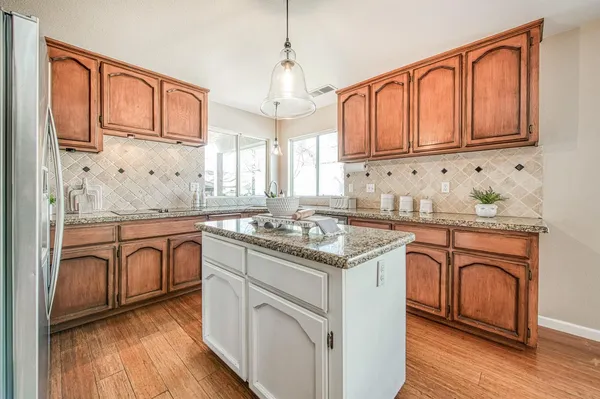 a kitchen with stainless steel appliances granite countertop a refrigerator oven stove a dining table and chairs with wooden floor