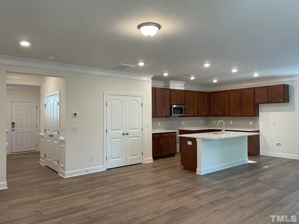 an open kitchen with kitchen island wooden floors and stainless steel appliances