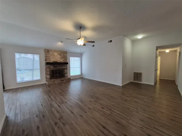 an empty room with wooden floor fireplace and staircase