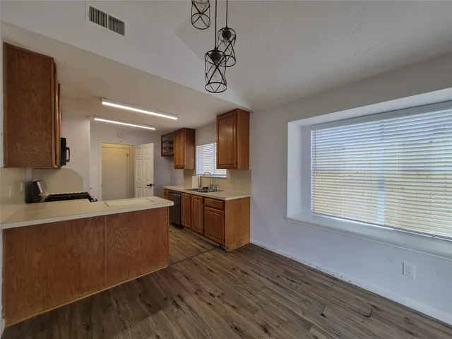 a large kitchen with stainless steel appliances granite countertop a sink dishwasher a stove and a refrigerator with wooden floor