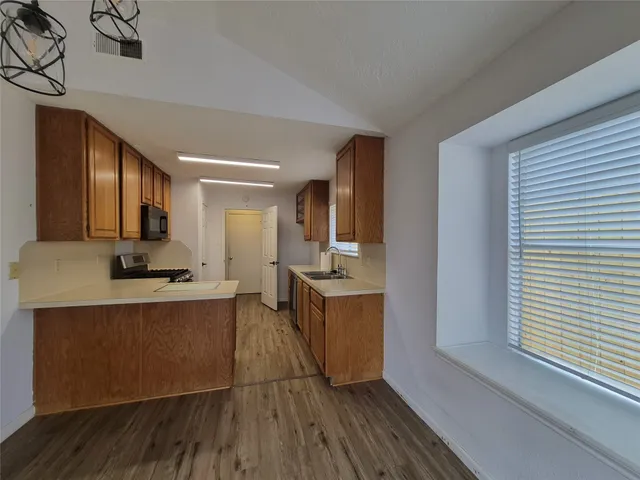 a kitchen with stainless steel appliances granite countertop a stove a sink dishwasher and a refrigerator with wooden floor