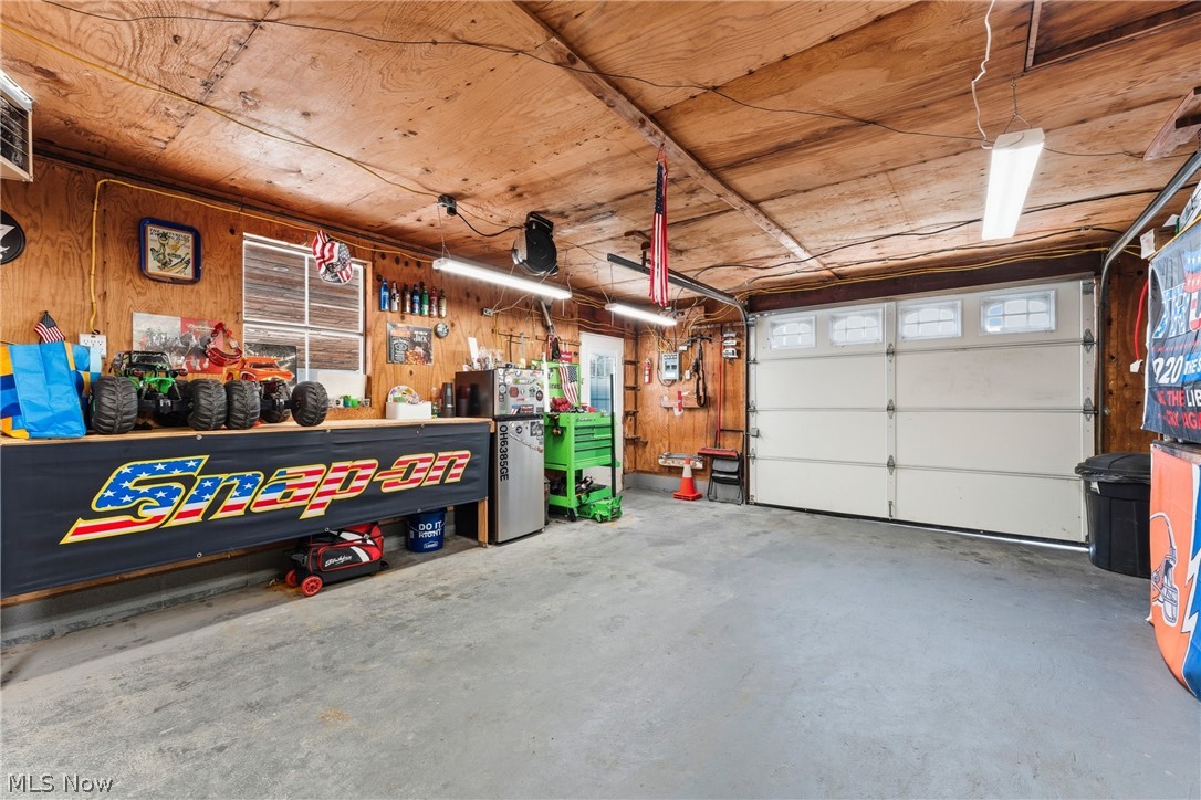 258 Randolph Road Mogadore, OH 44260 - Photo 29 of 49 Spacious garage featuring a sectional garage door with upper-row windows, concrete flooring, exposed wood ceiling, and built-in shelving