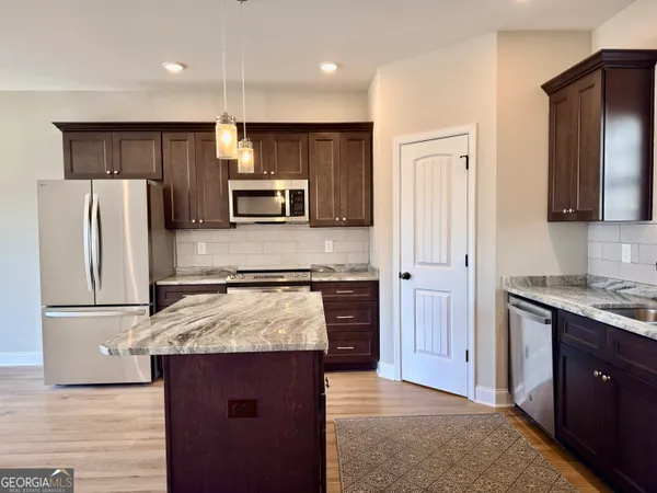 a kitchen with kitchen island granite countertop stainless steel appliances and wooden cabinets