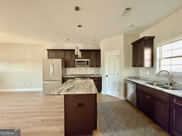 a kitchen with stainless steel appliances granite countertop a sink stove and refrigerator