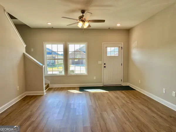 an empty room with wooden floor and windows