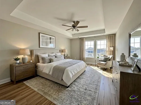 a spacious bedroom with a large bed a chandelier and windows