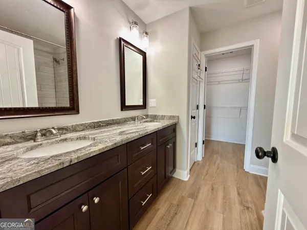 a spacious bathroom with a granite countertop double vanity sink a mirror and a shower